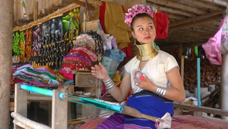 A-Young-Kayan-Saleswoman-Weaves-Traditional-Cloth-On-A-Loom-From-The-Kayan-Hill-Tribe-In-Baan-Tong-Luang,-Chiang-Mai,-Thailand