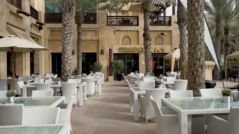 Empty-Chairs-And-Tables-Of-Bars-And-Restaurants-Under-The-Palm-Trees-In-Madinat-Jumeirah-Resort-In-Dubai,-United-Arab-Emirates
