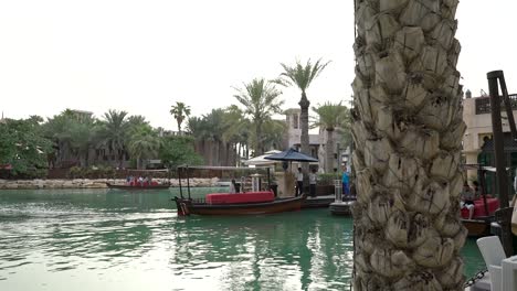 Abra-Boat-With-Tourists-Crossing-At-The-Waterway-In-Madinat-Jumeirah,-Dubai,-United-Arab-Emirates