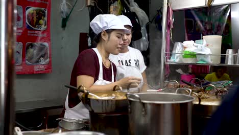 Beautiful-Thai-Woman-Serving-Hot-Soup-In-A-Food-Stall-In-Chinatown,-Bangkok,-Thailand---close-up