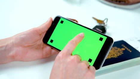 Woman's-Hands-Clicking-on-Green-Screen-Cell-Phone-with-Canadian-Passport,-Keys,-and-Wallet-in-Background---At-60-fps