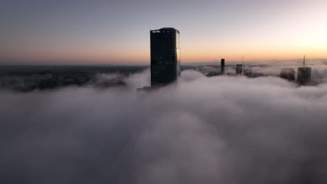 Aerial-shot-above-a-cloudy-foggy-Brisbane-City,-with-only-the-tops-of-sky-scrapers-being-visible