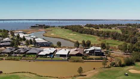 Yarrawonga,-Victoria,-Australia---3-March-2023:-Aerial-of-golf-course-billabong-and-houses-with-hotel-in-the-background