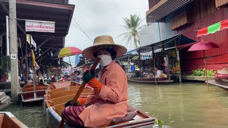 View-of-vendors-using-rowing-boats-to-navigate-the-narrow-canals-in-Damnoen-Saduak-Floating-Market-canals,-Ratchaburi-province,-South-West-of-Bangkok,-Thailand