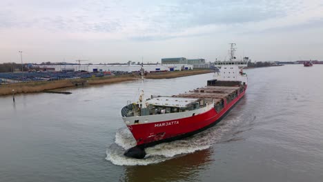 Empty-cargo-ship-navigating-inland-on-the-oude-maas-canal-in-Zwijndrecht,-The-Netherlands-on-a-cloudy-day-
