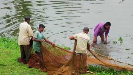 A-group-of-Fishermen-gathering-and-setting-their-fishing-nets-up-on-the-grass-with-the-river-in-the-background