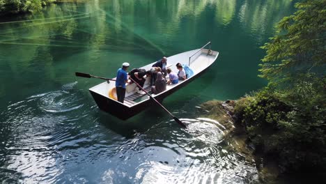 Multiethnische-Touristen-Genießen-Eine-Fahrt-Mit-Einem-Glasboden-Quellenboot-Und-Beobachten-Fische-Im-Kristallklaren-Türkisfarbenen-Wasser-Des-Berühmten-Alpensees-Blausee-Im-Kandergrund,-Schweiz