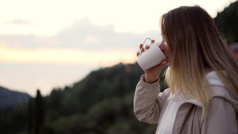 Blonde-woman-admiring-view-of-the-mountains-sipping-a-drink