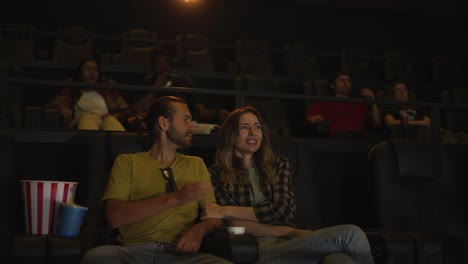 Beautiful-girl-looking-scary-while-watching-film-and-snuggling-to-her-boyfriend-sitting-next-to-her