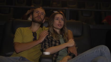 Blonde-girl-looking-scary-while-watching-film,-her-boyfriend-calming-her-down