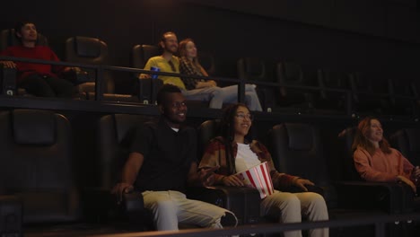 Mixed-raced-young-couple-sitting-in-movie-theatre-and-watching-film
