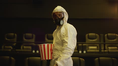 A-man-in-white-protection-costume-and-respirator-came-alone-to-the-cinema-with-bucket-of-popcorn