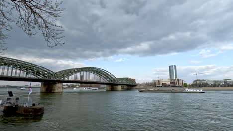 Lastkahn,-Der-Entlang-Des-Rheins-In-Richtung-Hohenzollernbrücke-In-Köln-Fährt,-Vom-Rheingarten-Aus-Gesehen