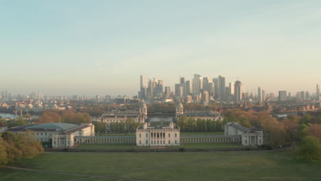 Aerial-shot-over-London-Maritime-Museum,-through-university-of-Greenwich-towards-Canary-Wharf-at-sunrise