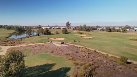 Yarrawonga,-Victoria,-Australia---18-April-2023:-Rising-up-over-the-Black-Bull-Golf-Course-with-golfers-walking-to-the-green-to-putt-out