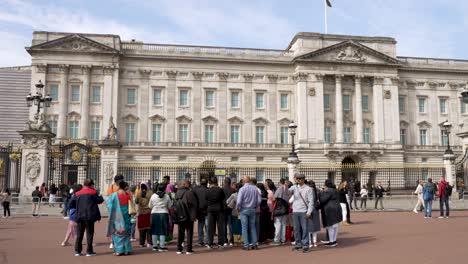 Tourist-Group-Sightseeing-With-Tour-Leader-Outside-Buckingham-Palace