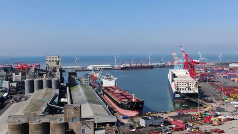 Containerschiffe-Und-Kräne-Im-Royal-Seaforth-Dock-Am-Fluss-Mersey-Mit-Windkraftanlagen-Und-Stahlterminal-Im-Hintergrund