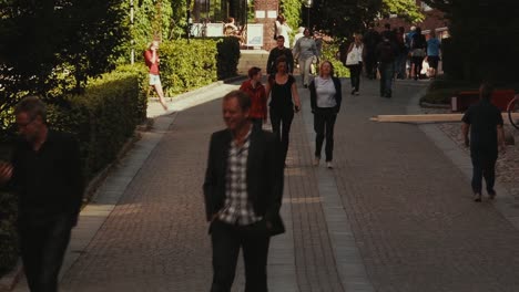 Men-and-women-walk-down-a-wide-brick-path-outside-on-a-bright-warm-afternoon