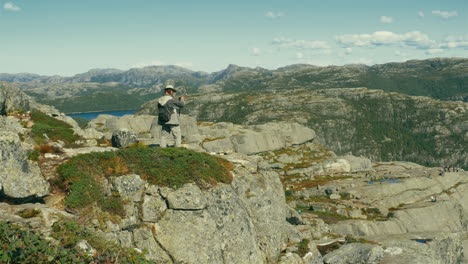 Enthusiastic-traveller-clicking-photographs-on-the-edge-of-Preikestolen-Pulpit-Rock