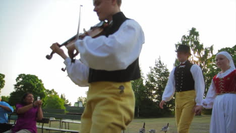 Happy-and-smiling-Scandinavians-demonstrate-the-very-traditional-art-of-folk-dancing-for-a-crowd-of-spectators-as-musicians-play-the-violin