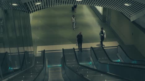 Una-Toma-En-Movimiento-En-Una-Escalera-Mecánica-Que-Se-Mueve-Hacia-Abajo-Con-Algunas-Personas-Subiendo-A-La-Escalera-Mecánica-En-El-Metro-De-Estocolmo