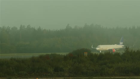 An-airplane-taking-off-while-another-airplane-taxiing-towards-the-runway,-on-a-foggy-day-at-Stockholm-Arlanda