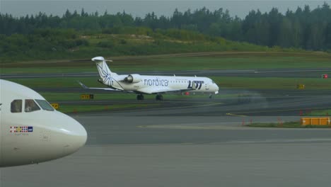 A-small-aircraft,-appearing-from-behind-a-larger-airplane,-taxiing-towards-the-runway-at-Stockholm-Arlanda