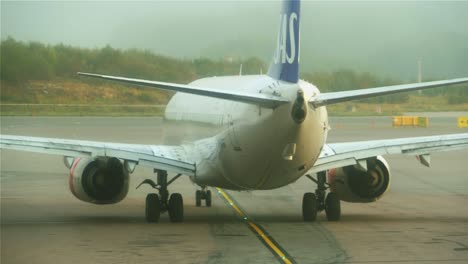 Close-up-of-an-airplane-heading-towards-the-runway-on-a-foggy-day-at-Stockholm-Arlanda