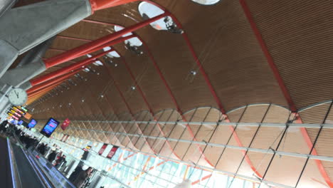 Fahren-Auf-Einem-Express-Gehweg-Im-Modernen-Flughafenterminalgebäude,-Einzigartiges-Design-Und-Architektur-Des-Flughafens-Madrid-Barajas,-Kombination-Von-Holz,-Stahl-Und-Beton,-Niederländischer-Blickwinkel-Mit-Fokus-Auf-Die-Uhr-Am-Ende