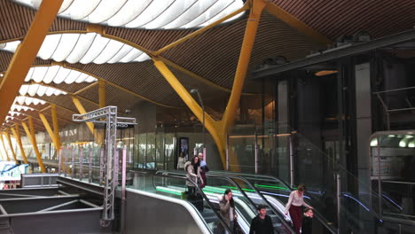 Modern-airport-terminal-with-people-using-escalators,-contemporary-architectural-design-combining-steel-and-wood-with-large-translucent-windows-in-the-ceiling,-travel,-transportation-and-architecture