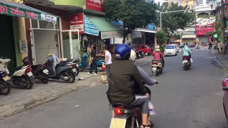 Bikes-and-cars-driving-by-storefront-in-Da-Nang,-Vietnam