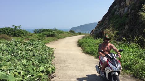 Man-driving-bike-down-a-quiet-road-on-a-mountain-in-Da-Nang,-Vietnam