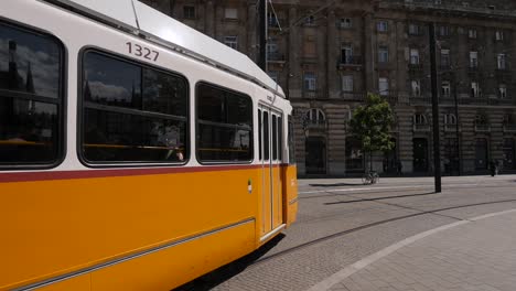 Yellow-tram-arriving-to-Kossuth-Lajos-square-in-Budapest,-Hungary