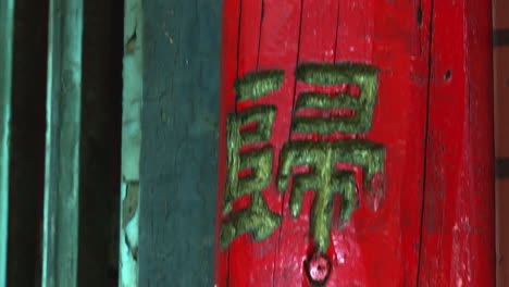 Chinese-characters-adorn-a-bright-red-wooden-door-post,-tilt-down
