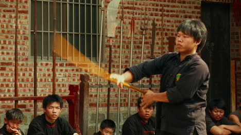 Young-man-twirls-kung-fu-spear-as-other-martial-arts-students-watch