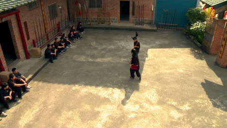 Female-martial-artist-learners-practicing-at-dojo-with-spectators-watching