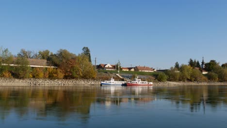 Small-tourist-boats-anchored-at-the-riverbank-in-Tahitotfalu,-Hungary