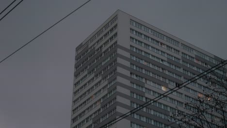 Low-Angle-View-Of-Apartment-Building-In-Early-Evening-Against-Dark-Clouds