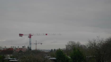 Construction-Cranes-In-The-Distance-Against-Dramatic-Clouds-In-Urban-City