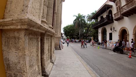 In-a-street-in-the-old-town-of-Cartagena-de-Indias,-several-people-are-walking-by