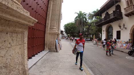 An-afro-American-Colombian-is-walking-in-a-street-in-the-old-town-of-Cartagena-close-to-a-huge-old-door
