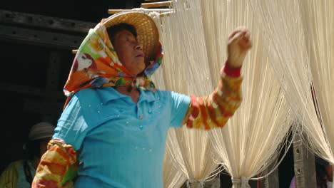 Factory-worker-in-China-checking-racks-of-raw-noodles-hung-out-to-dry-in-the-warm-afternoon-sunlight