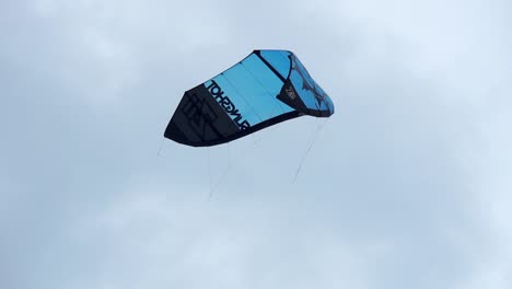 A-blue-kite-for-kitesurfing-is-floating-in-the-air-below-a-blue-sky