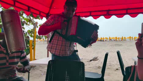 A-man-plays-the-accordion-next-to-a-man-who-plays-the-caja-and-guacharaca