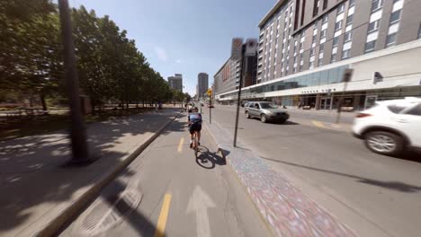 POV-Behind-Cyclists-Along-Sunny-Berri-Street-In-Montreal,-Canada