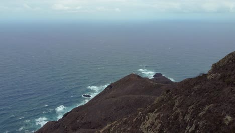 Tourists-Sit-On-Rocky-Peak-In-Anaga-Rural-Park-With-Overview-Of-Atlantic-Ocean-In-Tenerife,-Canary-Islands,-Spain