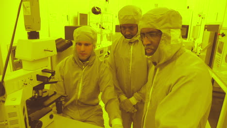 Three-Hospital-Worker-in-Protective-Clothing-Looking-at-Microscope-Results,-Medium,-Slowmo