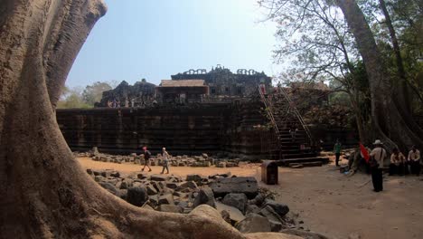 An-enormous-tree,-ruins-set-to-mark-a-path-and-a-temple-in-the-Angkor-Archaeological-Park