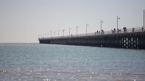Beautiful-pier-on-sunny-warm-day-with-blue-sky-people-walking-and-fishing