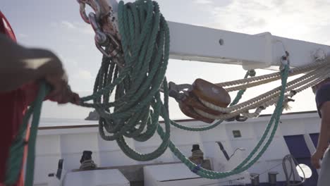 A-man-or-sailor-is-putting-and-organizing-the-green-rope-over-a-crane-on-the-front-deck-of-a-cruise